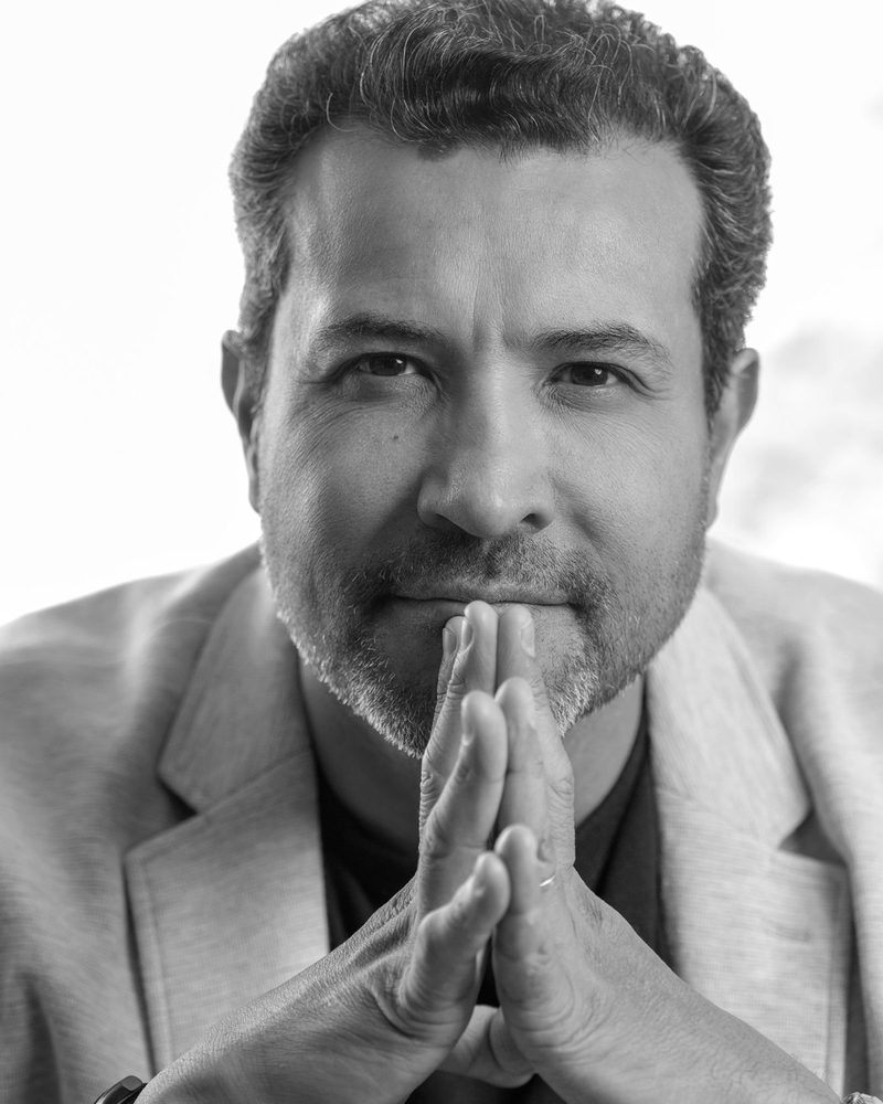 Ulrick Noel with his hands steepled, black-and-white portrait